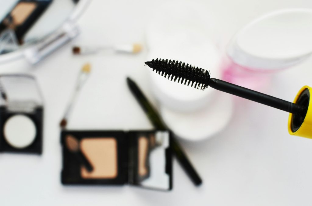 Flat lay of cosmetics featuring a mascara brush, perfect for beauty and fashion themes.