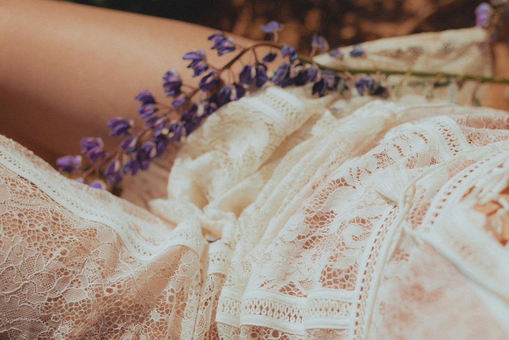 Elegant close-up of intricate lace fabric paired with delicate purple flowers.