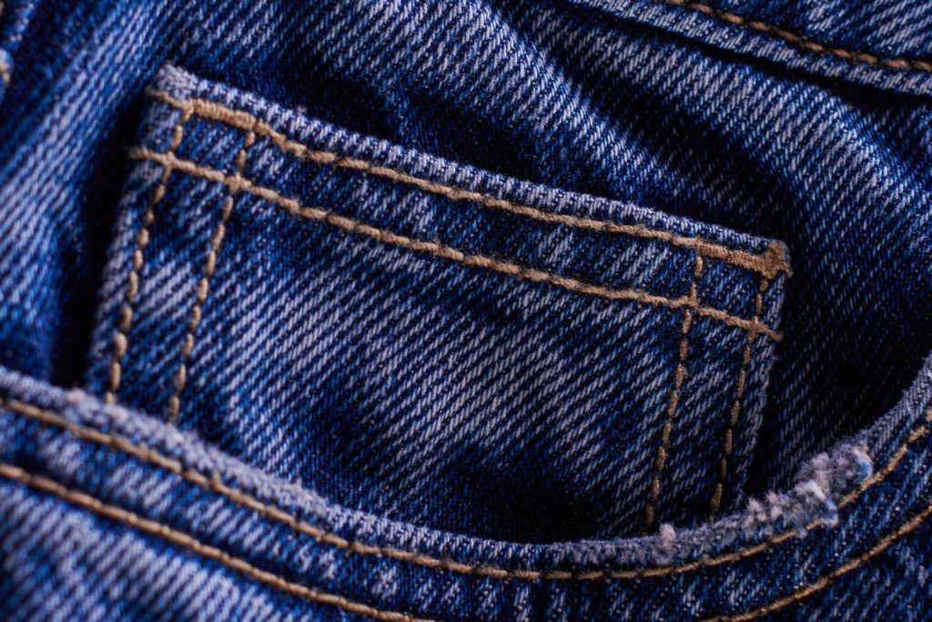 Detailed close-up of a blue denim jeans pocket showing texture and stitching.